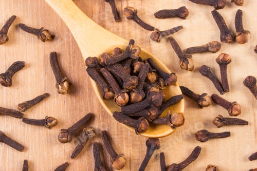 Preview: Heap Of Brown Cloves On Wooden Spoon Lying On Wooden Table, Seasoning For Baking And Cooking