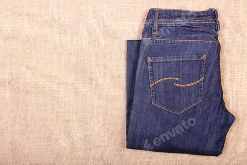 Preview: Pair Of Pants Jeans On Jute Burlap, Womanly Clothing, Place For Text Or Inscription