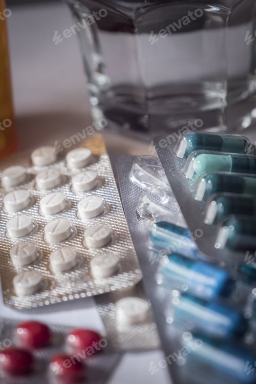 Vista previa: Some Pills Of Different Size And Color Along With A Water Glass