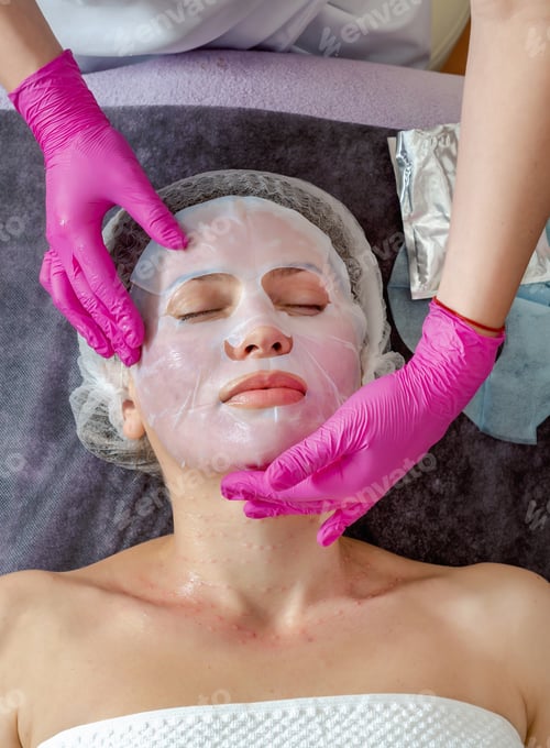Preview: Hands Of Beautician In Rubber Gloves Smoothes Collagen Hydrogel Mask On Woman Face In A Beauty Salon