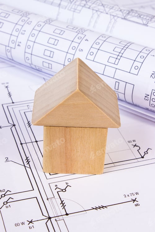 Preview: House Shape Made Of Wooden Blocks And Rolls Of Diagrams Lying On Electrical Construction Drawings