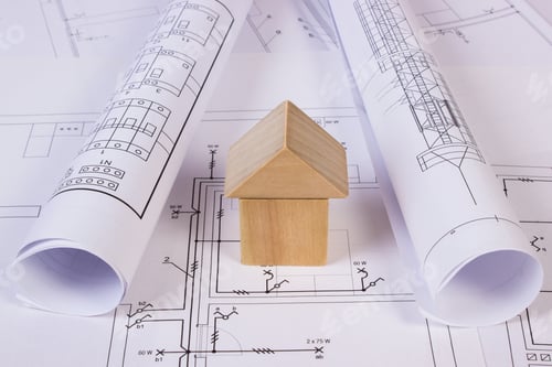 Preview: House Shape Made Of Wooden Blocks And Rolls Of Diagrams Lying On Electrical Construction Drawings