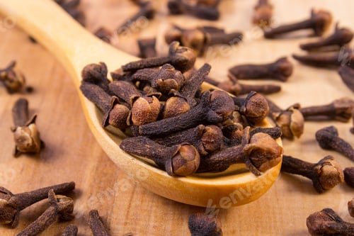 Preview: Heap Of Brown Cloves On Wooden Spoon Lying On Wooden Table, Seasoning For Baking And Cooking