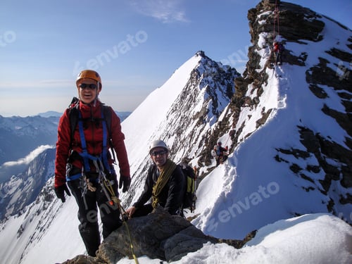Preview: Woman And Man Mountain Climber On The Way To A High Mountain Peak Along A Narrow Rocky Ridge