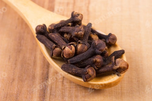 Preview: Heap Of Brown Cloves On Wooden Spoon Lying On Wooden Table, Seasoning For Baking And Cooking
