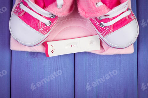 Preview: Pregnancy Test With Positive Result And Clothing For Newborn On Purple Boards, Concept Of Extending