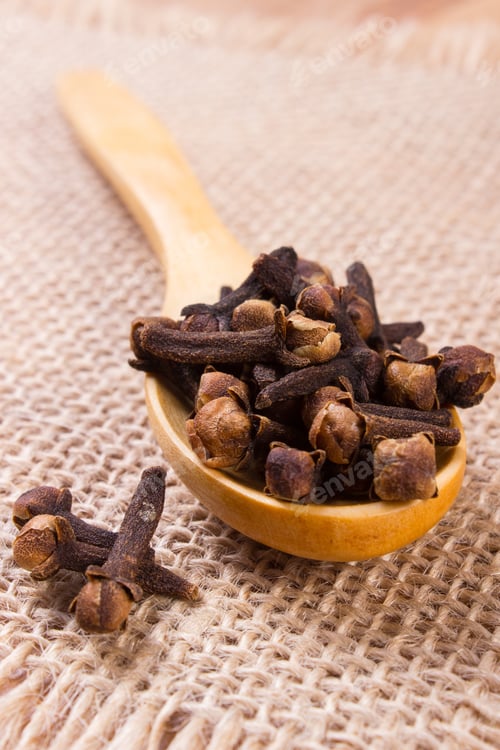 Preview: Heap Of Brown Cloves On Wooden Spoon Lying On Jute Canvas, Seasoning For Baking And Cooking