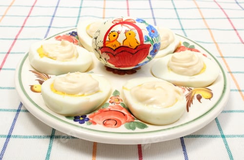 Preview: Halves Of Eggs With Mayonnaise And Colorful Painted Easter Egg Lying On Colorful Plate, Sliced Egg