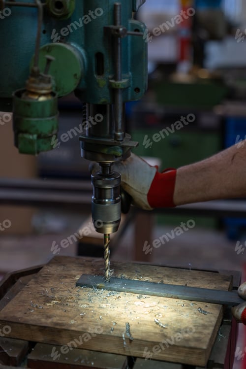 Preview: A Metal Worker Drilling Holes In Metal With A Bench Drill