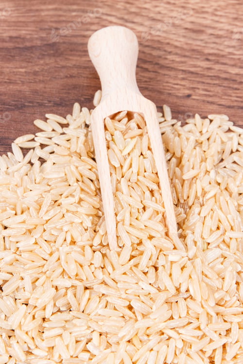 Preview: Heap Of Brown Rice With Wooden Scoop On Rustic Board, Concept Of Healthy Nutrition