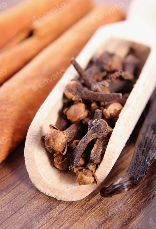 Preview: Closeup Of Fresh Cloves, Fragrant Vanilla Pods And Cinnamon Sticks On Wooden Surface Plank
