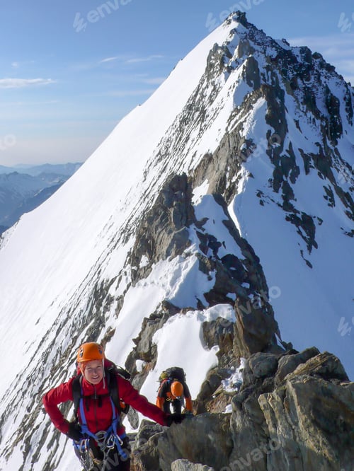 Preview: Male And Female Mountain Climber On An Exposed Rocky Summit Ridge On Their Way To A High Alpine