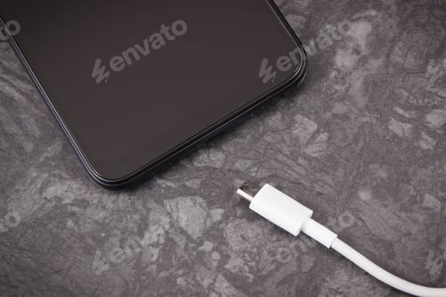 Preview: Black Mobile Phone And Unconnected Cable Of Charger. Smartphone Charging. Black Background