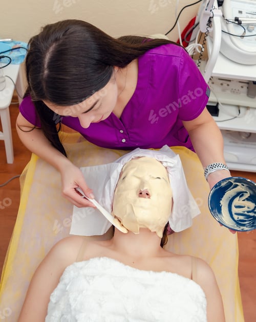 Preview: Beautician Applies Alginate Mask On Woman Patient Face In Cosmetology Clinic.