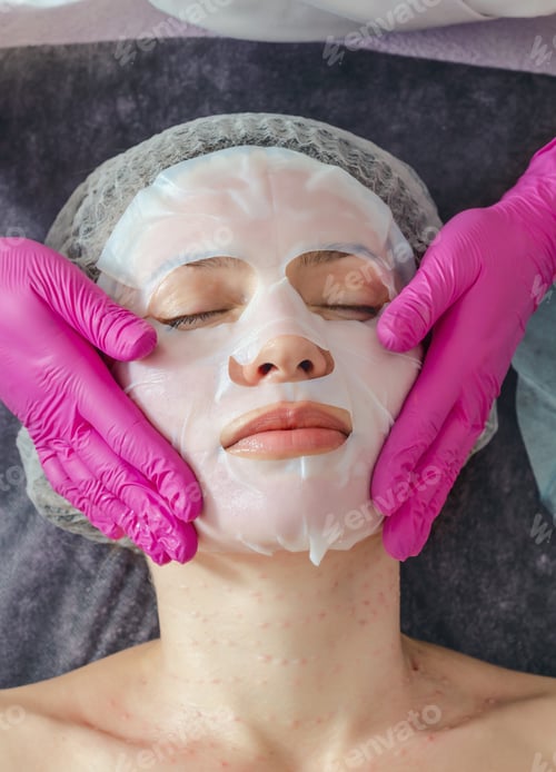 Preview: Hands Of Beautician In Rubber Gloves Smoothes Collagen Hydrogel Mask On Woman Face In A Beauty Salon
