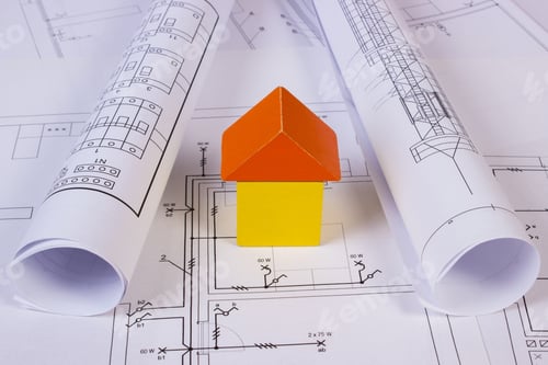 Preview: House Shape Made Of Wooden Blocks And Rolls Of Diagrams Lying On Electrical Construction Drawings