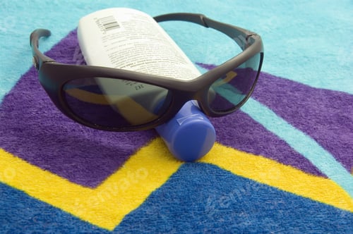 Preview: Sunglasses And Bottle Of Sunscreen On Beach Towel