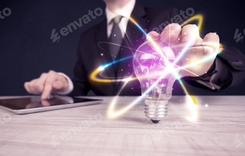 Preview: A Classy Businessman Holding A Colorful Light Bulb With Shining Circles In Front Of Dark Background