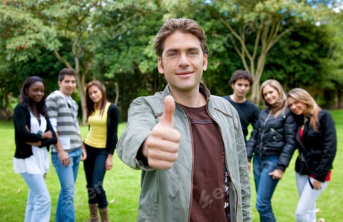 Preview: Man With Thumbs Up Outdoors And A Group Behind Him