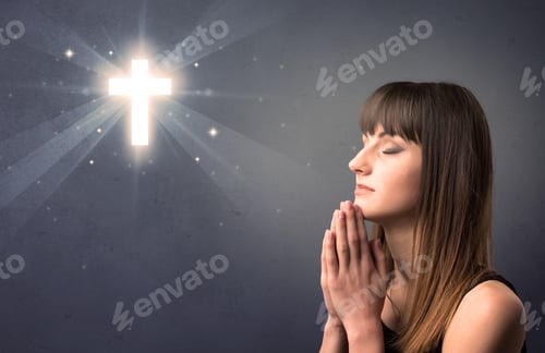 Preview: Young Woman Praying On A Grey Background With A Shiny Cross Above Her