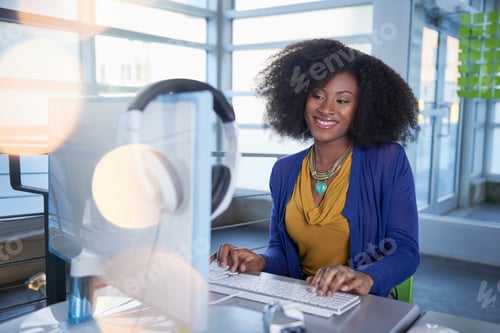 Preview: Portrait Of A Smiling Woman With An Afro At The Computer In Bright Glass Office
