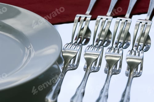 Preview: Four Forks And Their Reflections Against Light Blue Sky Beside A Dinner Plate