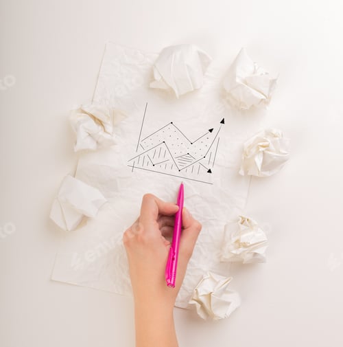 Preview: Female Hand Next To A Few Crumpled Paper Balls Drawing A Progress Chart