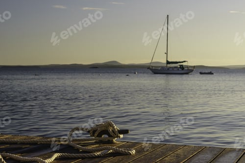 Preview: Coastal Study In Nautical Preference: Rope Tied To Cleat On Dock In Foreground To Secure A Boat Off