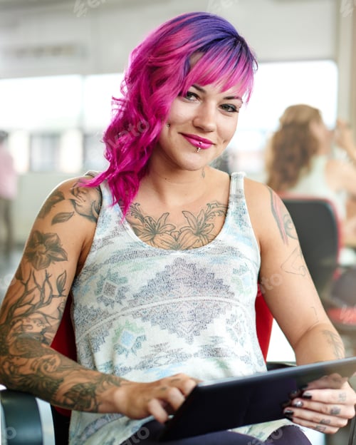 Preview: Confident And Edgy Female Designer Working On A Digital Tablet In Red Creative Office Space