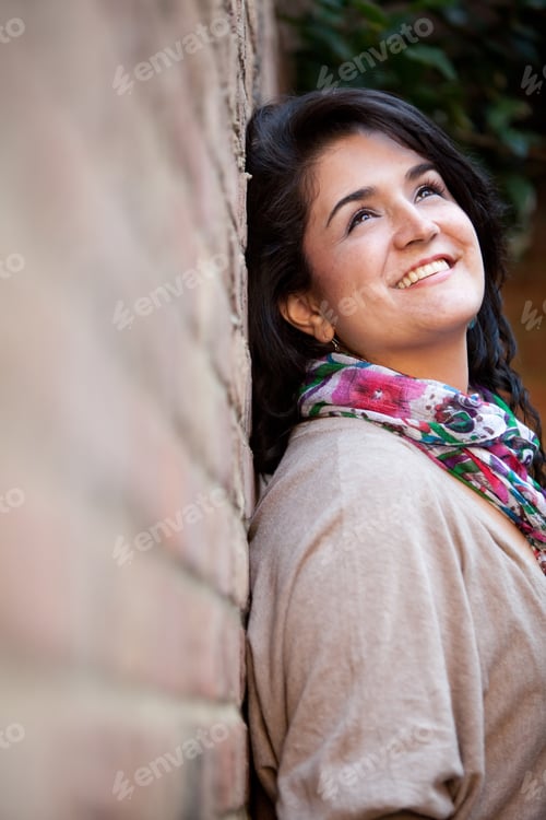 Preview: Pensive Woman Outdoors Leaning Against A Brick Wall