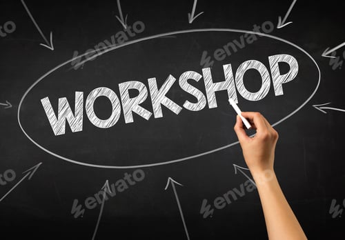 Preview: Female Hand Holding White Chalk In Front Of A Blackboard With Workshop Written On It