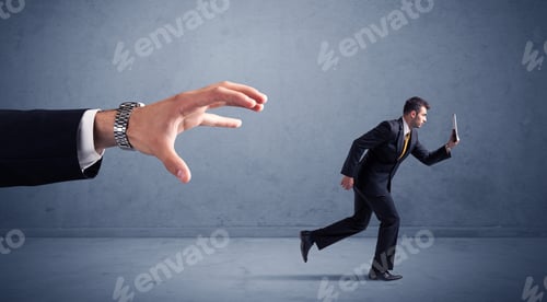 Preview: Young Miniature Businessman Running From A Big Hand With Blueish Background