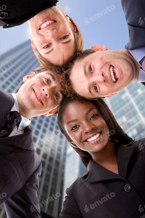 Preview: Business Team With Heads Together With Corporate Buildings Behind