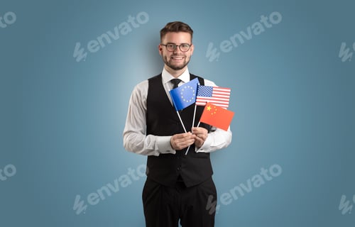 Preview: Cheerful Student Standing In Front Of Wall With National Flag On His Hand