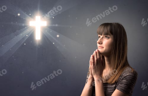 Preview: Young Woman Praying On A Grey Background With A Shiny Cross Above Her