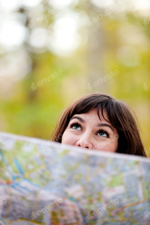 Preview: Woman Exploring Outdoors Holding A Map And Looking Lost
