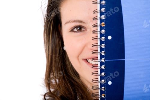 Preview: Female Student Peeping Behind A Notebook - Isolated Over A White Background