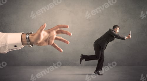 Preview: Young Miniature Businessman Running From A Big Hand With Grey Background
