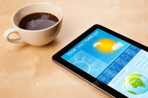 Preview: Workplace With Tablet Pc Showing Weather Forecast And A Cup Of Coffee On A Wooden Work Table