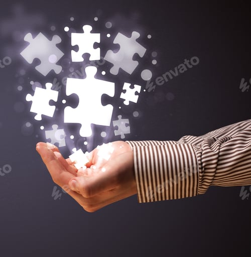 Preview: Businessman Holding Shining Puzzle Pieces In His Hand