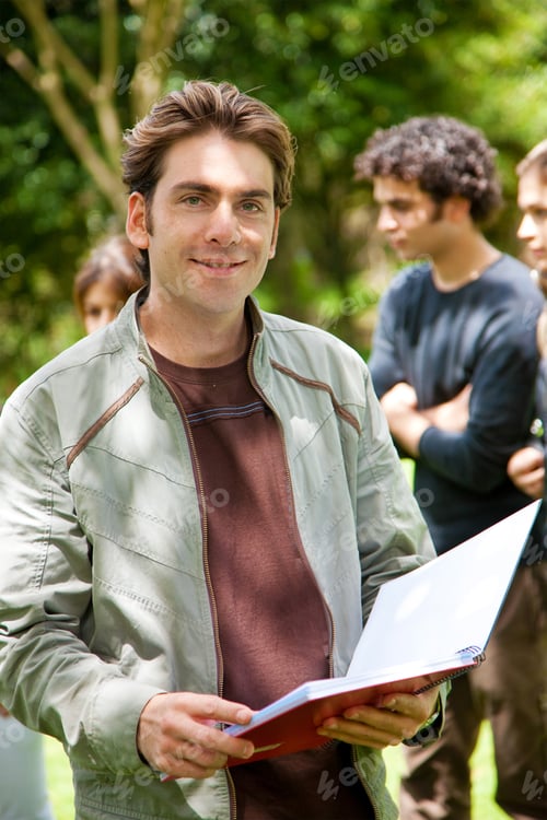 Preview: Handsome Male Student Holding A Notebook Outdoors