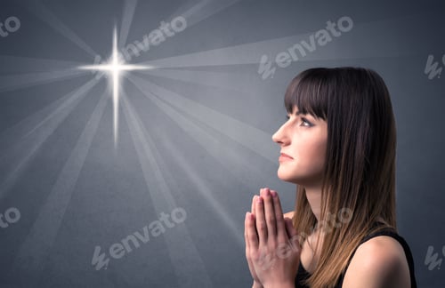 Preview: Young Woman Praying On A Grey Background With A Shiny Cross Silhouette Above Her