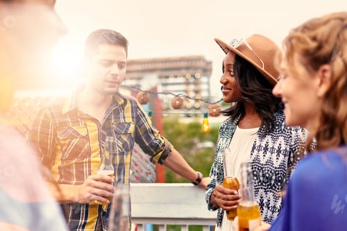 Preview: Multi-Ethnic Millenial Group Of Friends Partying And Enjoying A Beer On Rooftop Terrasse At Sunset