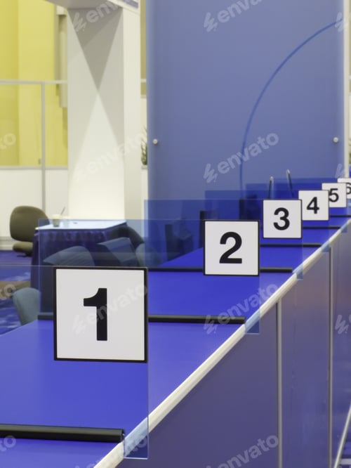 Preview: Numbered Stations Along Blue Registration Counter In Convention Hall