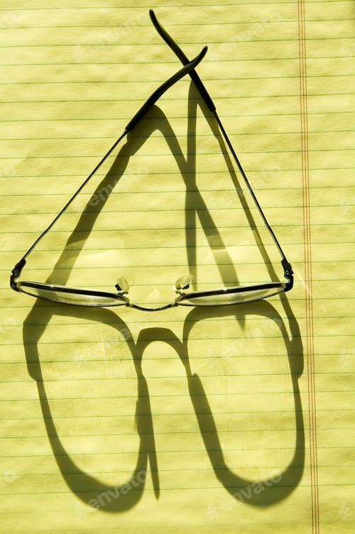 Preview: Reading Glasses Shadowed By Sunlight On Canary Paper