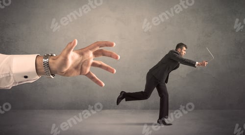 Preview: Young Miniature Businessman Running From A Big Hand With Grey Background