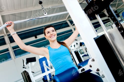 Preview: Woman Exercising Her Arms And Back At The Gym On A Machine