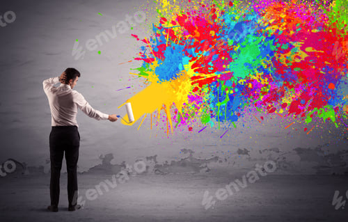 Preview: An Elegant Businessman In Suit Painting Colorful Splatter, Bright Colors On Grey Urban Wall With A