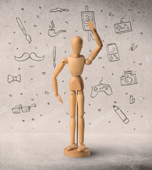 Preview: Wooden Mannequin Posed In Front Of A Greyish Background With Hobby Related Scribbles Behind It