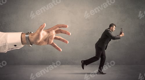 Preview: Young Miniature Businessman Running From A Big Hand With Grey Background